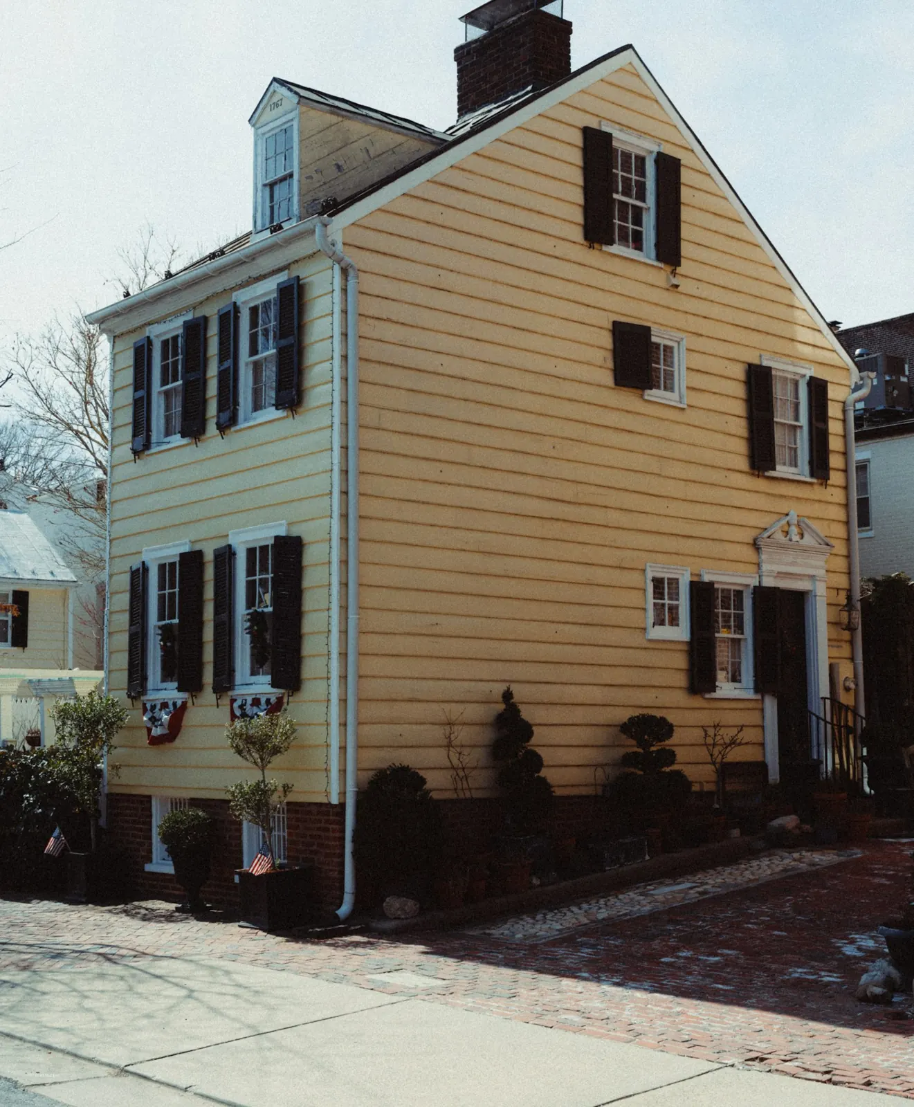 A yellow colonial style house with black shutters