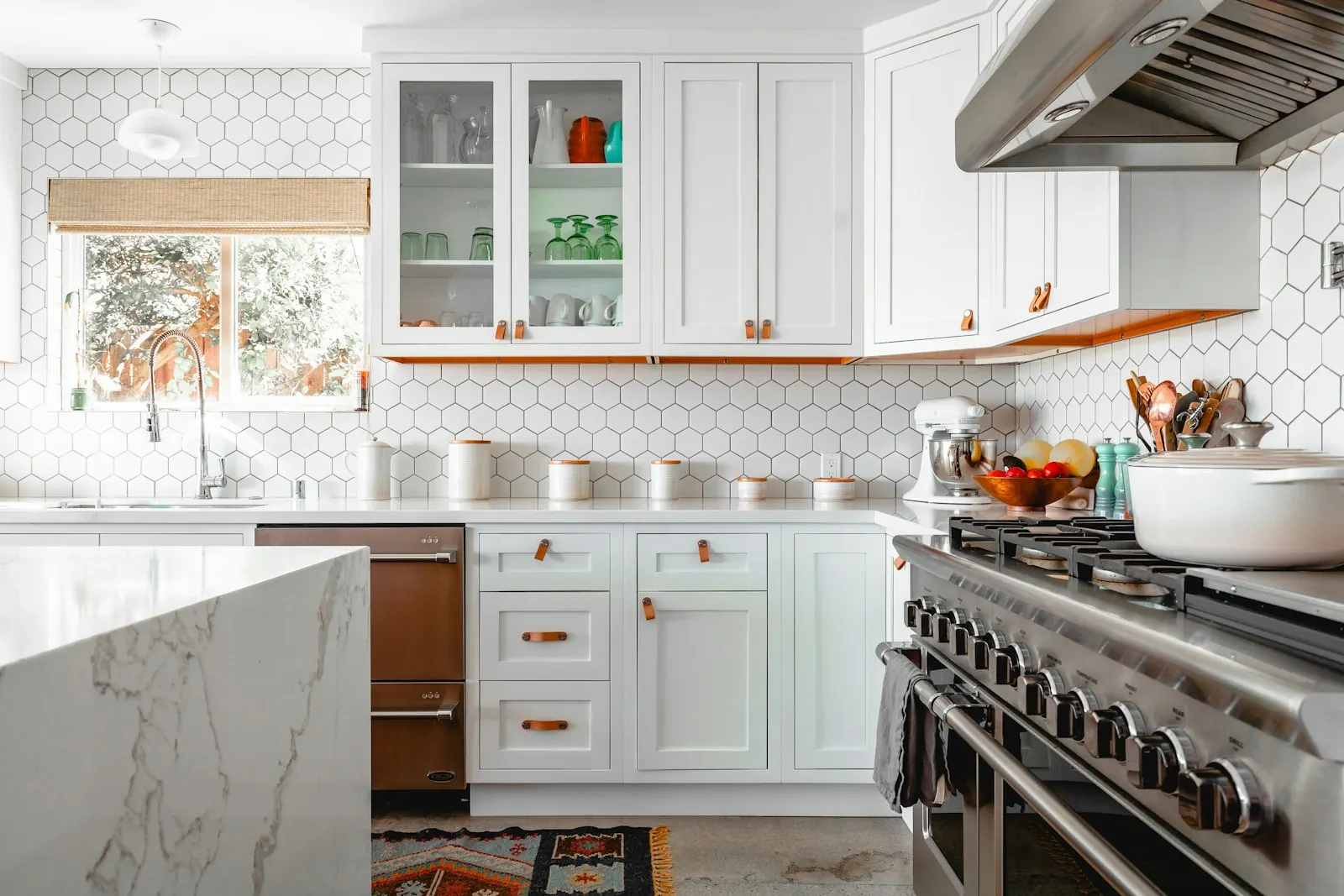 A finished kitchen with white cabinets and marble counters