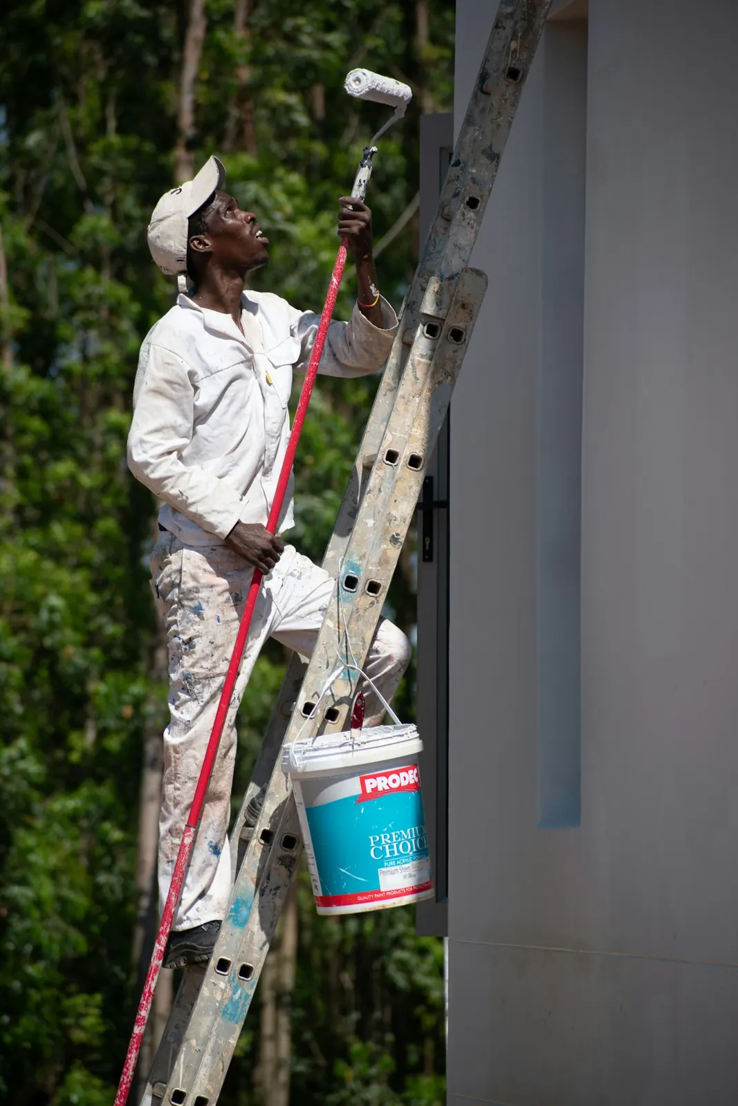 A painter on a ladder rolling paint onto a building